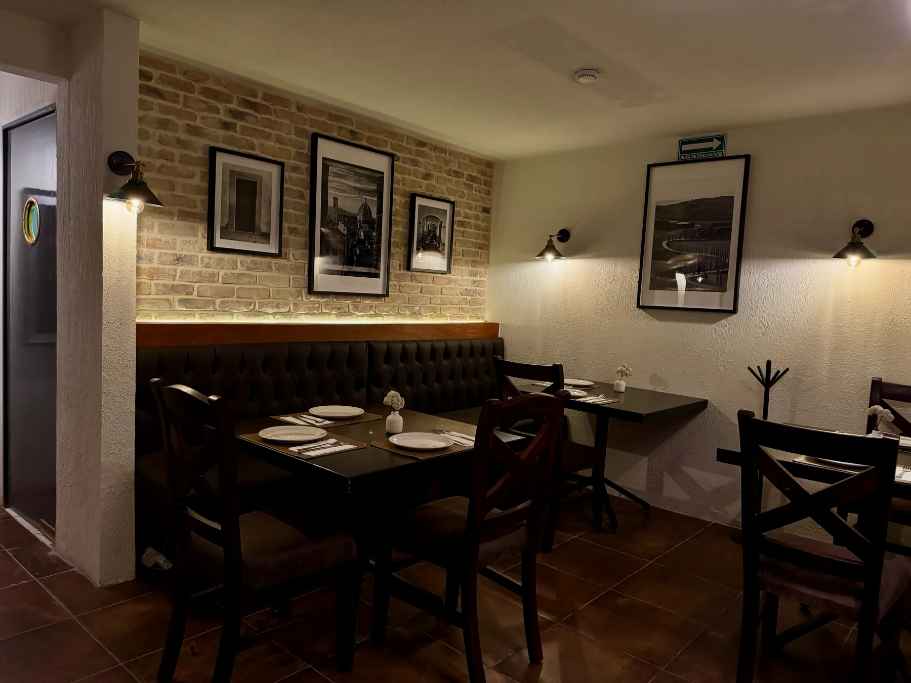 Salón interior con muro de ladrillo y fotografías antiguas