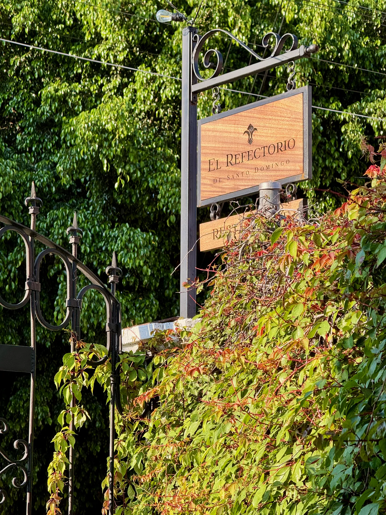 Letrero de El Refectorio entre la vegetación de la entrada